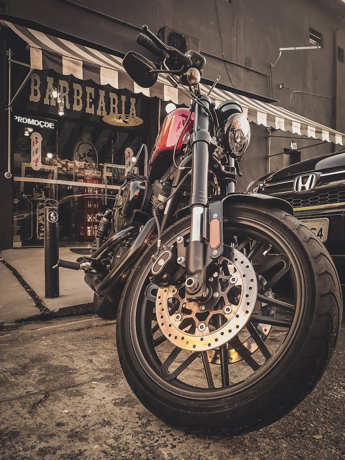 A stylish vintage motorcycle parked outside a classic barbershop with a rustic ambiance.
