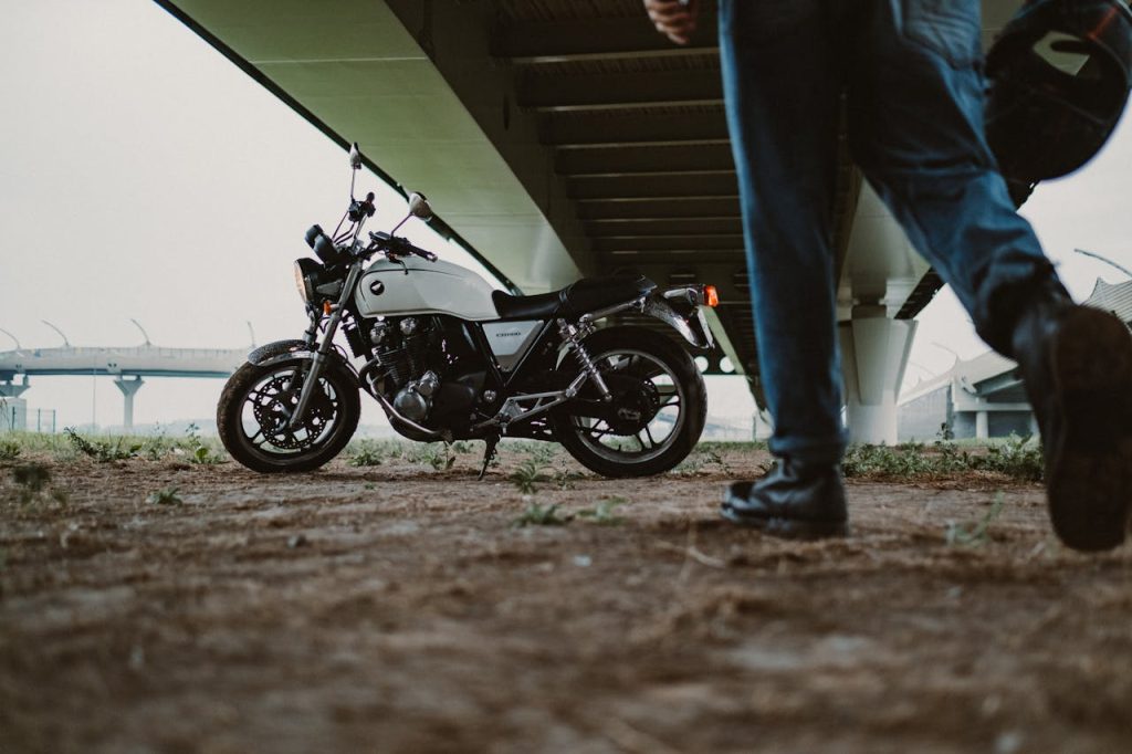 Motorcycle parked under a bridge with a person walking by, creating a dynamic urban scene.
