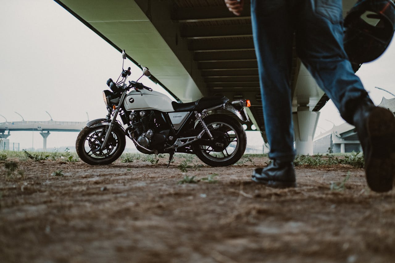 Motorcycle parked under a bridge with a person walking by, creating a dynamic urban scene.